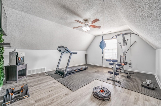 exercise room with visible vents, a ceiling fan, lofted ceiling, and wood finished floors