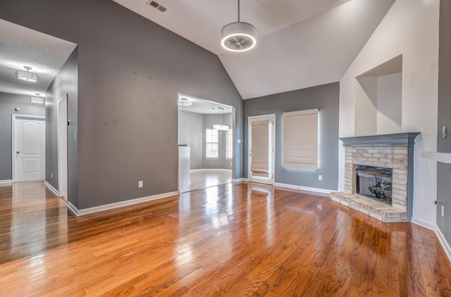 unfurnished living room with visible vents, a brick fireplace, and hardwood / wood-style floors