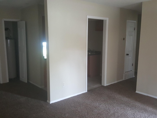 interior space featuring a sink, baseboards, carpet, and water heater