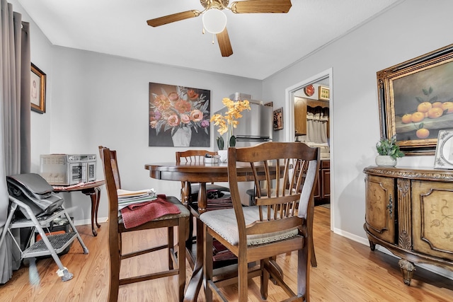 dining room featuring baseboards, ceiling fan, and light wood finished floors