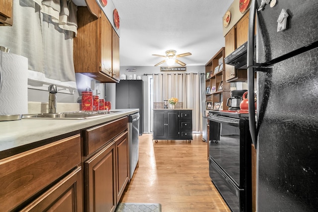 kitchen featuring a ceiling fan, a sink, black appliances, light countertops, and light wood-type flooring