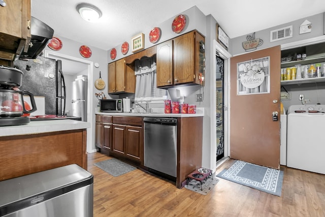 kitchen with visible vents, light wood finished floors, washer / clothes dryer, light countertops, and appliances with stainless steel finishes