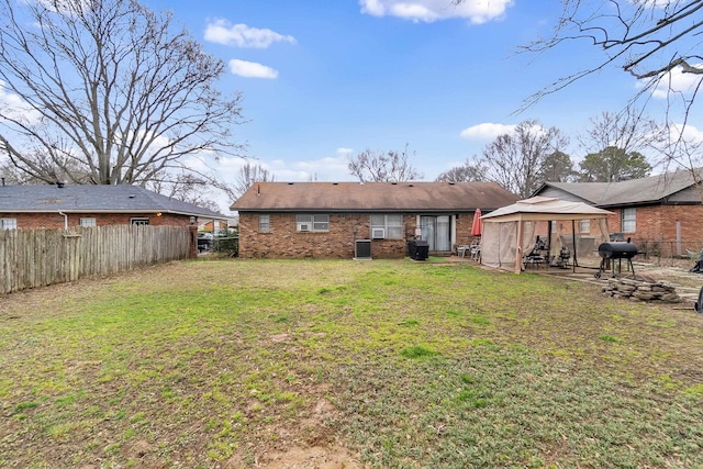 rear view of house with a yard, a gazebo, a patio area, fence private yard, and brick siding