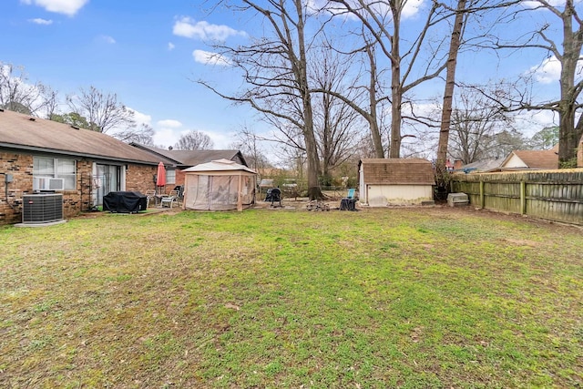 view of yard featuring a fenced backyard, central air condition unit, a storage unit, and an outdoor structure