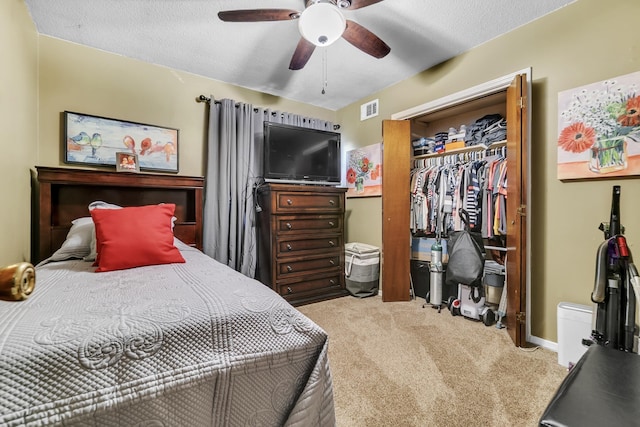 bedroom featuring visible vents, ceiling fan, a closet, a textured ceiling, and light colored carpet