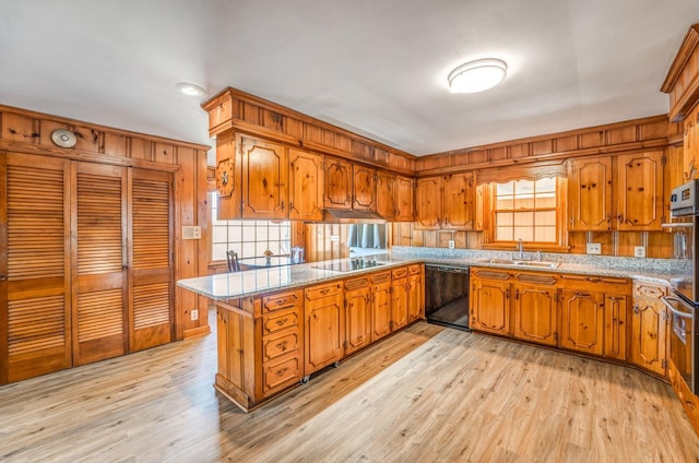 kitchen with a sink, brown cabinets, black appliances, and a peninsula