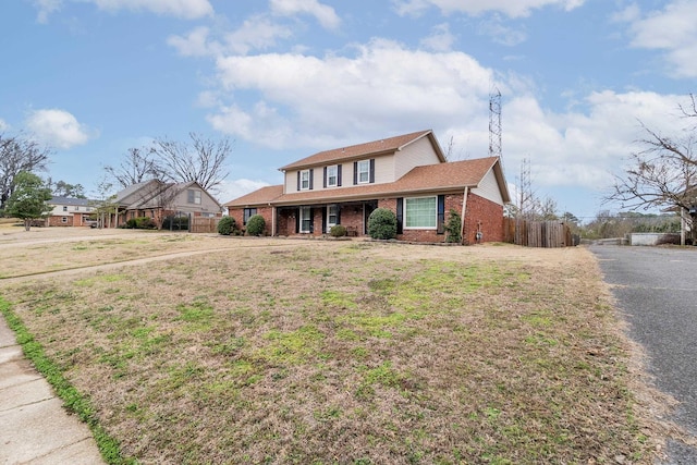 view of front of house featuring a front lawn, fence, and brick siding