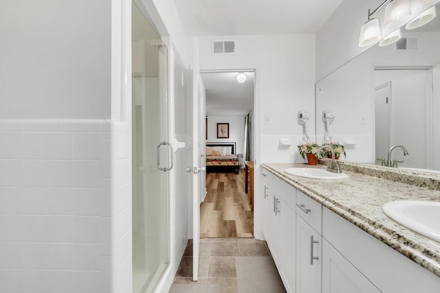 ensuite bathroom featuring visible vents, double vanity, a stall shower, ensuite bath, and a sink