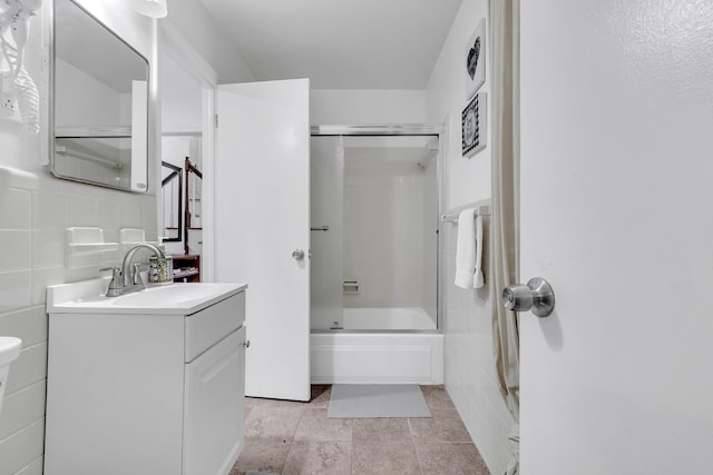 full bath with vanity, tile walls, and shower / bath combination with glass door