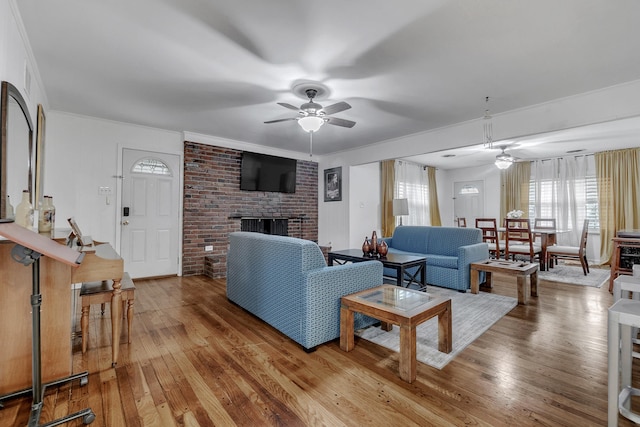 living area with a fireplace, light wood finished floors, and ceiling fan