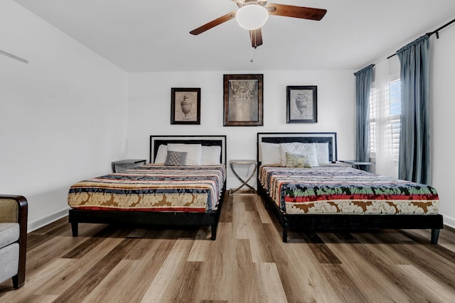 bedroom with a ceiling fan, wood finished floors, and baseboards