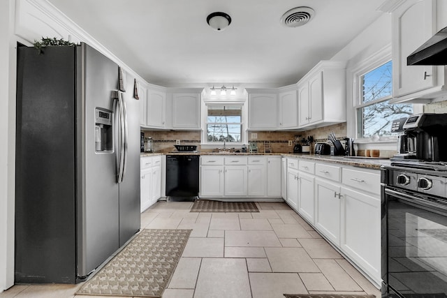 kitchen featuring visible vents, backsplash, wall chimney range hood, white cabinets, and black appliances