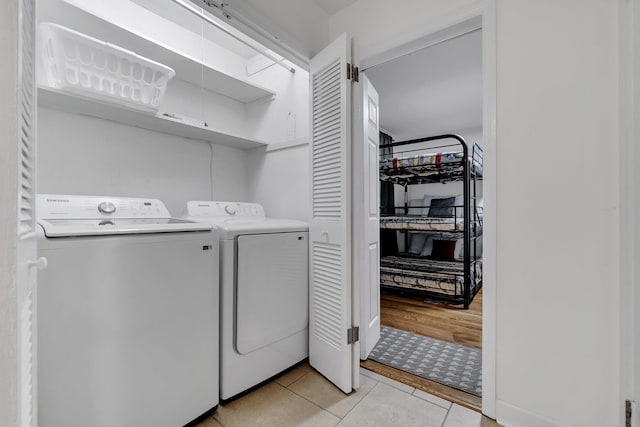 clothes washing area with light tile patterned flooring, laundry area, and washing machine and dryer