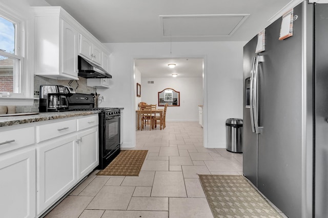 kitchen with black gas stove, under cabinet range hood, light stone counters, white cabinets, and stainless steel fridge