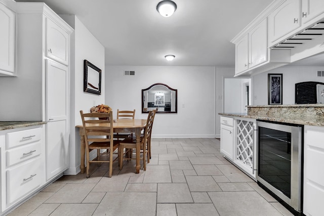 kitchen featuring wine cooler, visible vents, white cabinets, and light stone counters