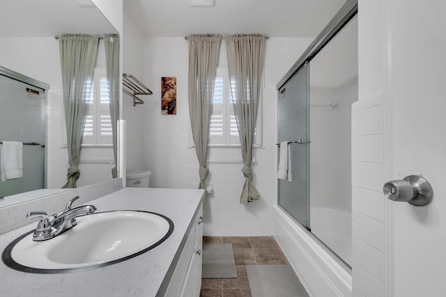 full bathroom featuring combined bath / shower with glass door, vanity, and tile walls