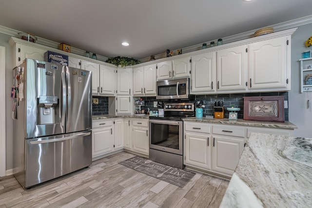 kitchen featuring light wood-type flooring, stainless steel appliances, tasteful backsplash, and white cabinets