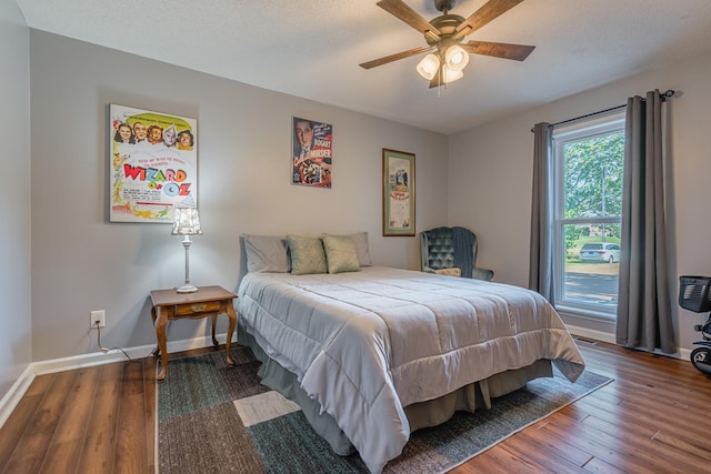 bedroom featuring a ceiling fan, wood finished floors, baseboards, and a textured ceiling