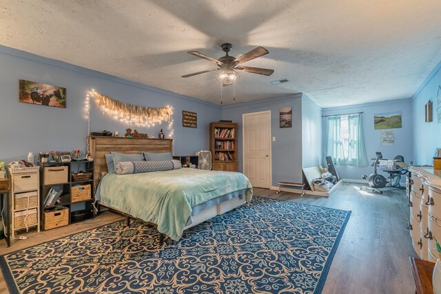 bedroom featuring visible vents, a textured ceiling, crown molding, and wood finished floors