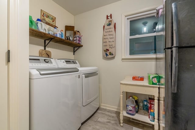 laundry area with baseboards, independent washer and dryer, laundry area, and light wood finished floors
