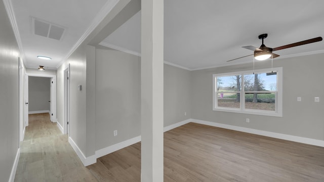 spare room featuring crown molding, baseboards, visible vents, and light wood finished floors