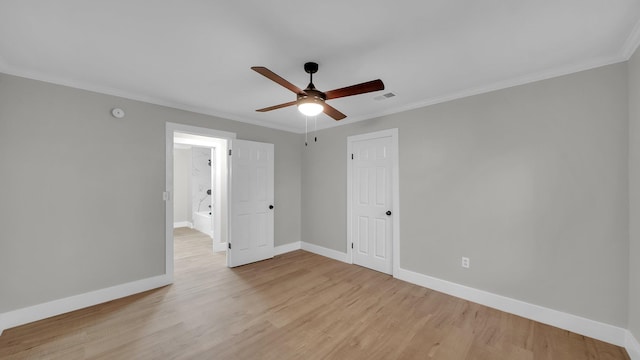 spare room featuring light wood-style flooring, crown molding, and baseboards