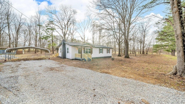 view of front of home with a detached carport, driveway, and a chimney