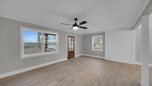 spare room featuring light wood-style flooring, a ceiling fan, baseboards, and ornamental molding