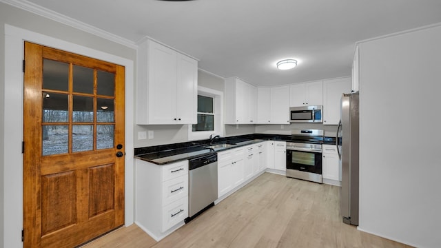 kitchen featuring a sink, white cabinets, light wood-style floors, appliances with stainless steel finishes, and crown molding