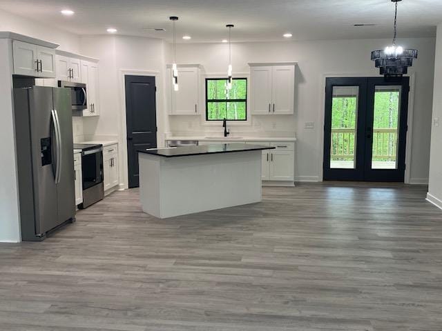 kitchen featuring light wood-style flooring, a sink, a kitchen island, french doors, and appliances with stainless steel finishes