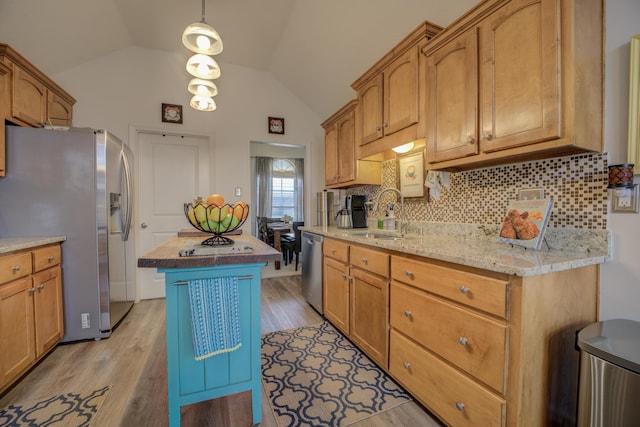 kitchen with a sink, vaulted ceiling, light wood-style floors, appliances with stainless steel finishes, and butcher block counters