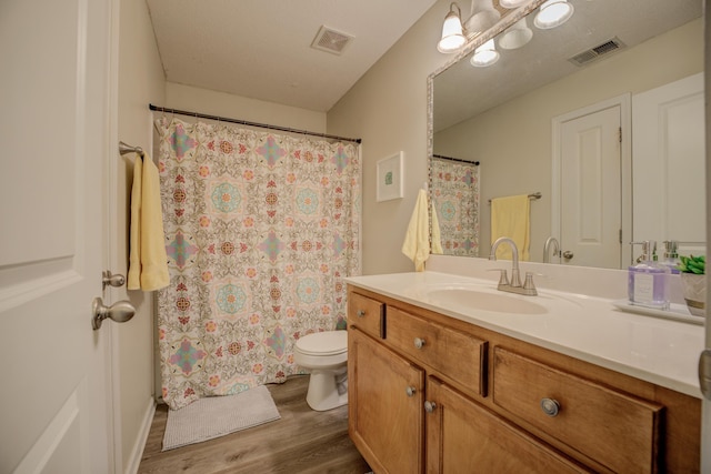 bathroom featuring visible vents, toilet, wood finished floors, and vanity