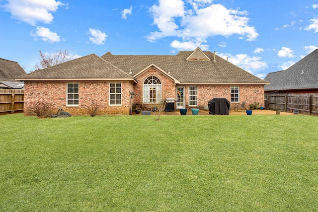 back of property with a yard, brick siding, and a fenced backyard