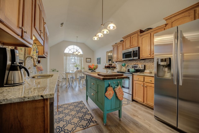 kitchen featuring light wood finished floors, lofted ceiling, a sink, stainless steel appliances, and backsplash