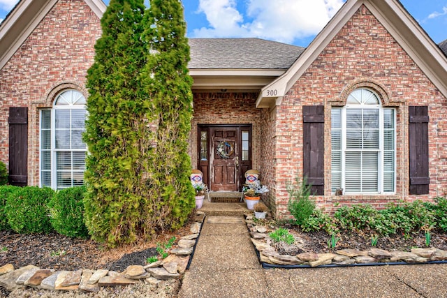 view of front of home featuring brick siding and roof with shingles