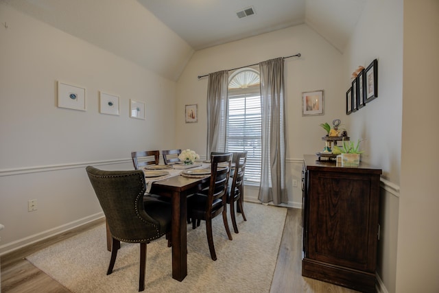 dining room with visible vents, lofted ceiling, baseboards, and light wood finished floors