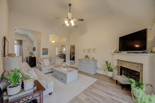 living room with a ceiling fan, baseboards, lofted ceiling, light wood-style flooring, and a fireplace