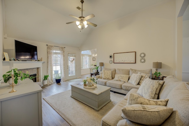 living area featuring visible vents, high vaulted ceiling, a fireplace, ceiling fan, and light wood-type flooring