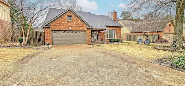 traditional-style house with fence, driveway, a chimney, a garage, and brick siding