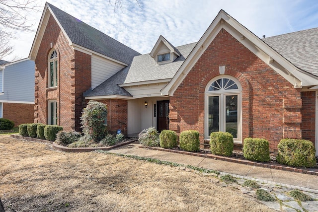 view of front of property featuring brick siding and a shingled roof