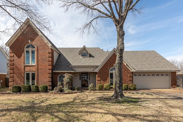 view of front of property featuring driveway, roof with shingles, a front yard, an attached garage, and brick siding