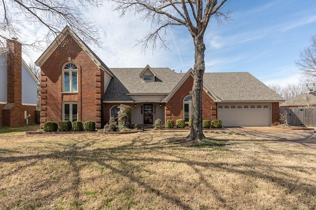 view of front of property featuring fence, roof with shingles, a front lawn, a garage, and brick siding