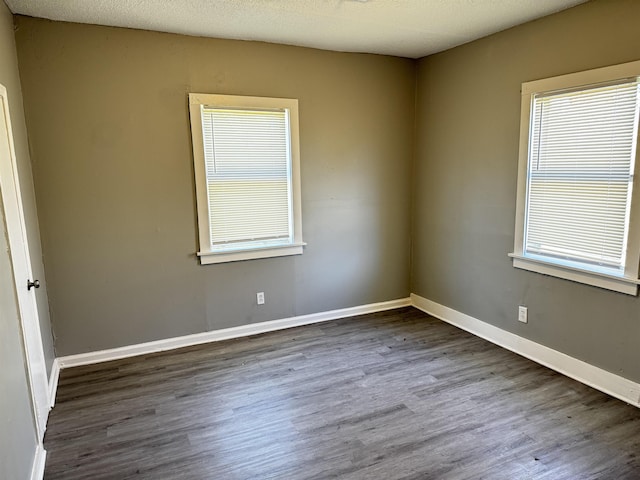 spare room with dark wood finished floors, a healthy amount of sunlight, baseboards, and a textured ceiling