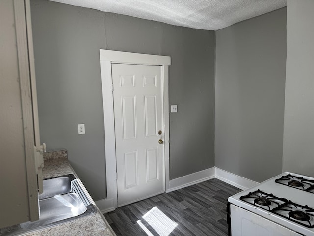 kitchen with baseboards, light countertops, white range with gas cooktop, dark wood-style floors, and a textured ceiling