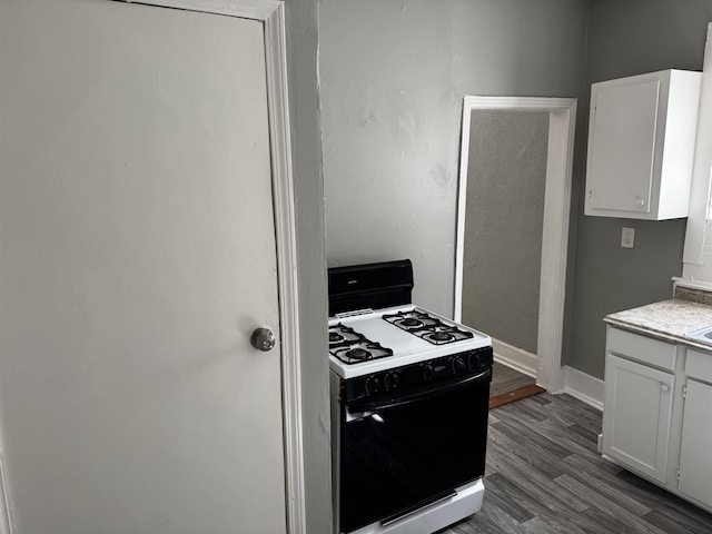 kitchen featuring white cabinetry, dark wood-type flooring, gas stove, and light countertops