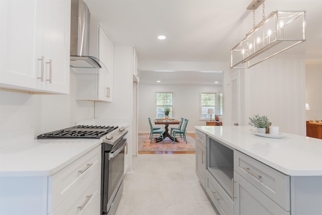 kitchen featuring built in microwave, light countertops, white cabinets, stainless steel gas range oven, and wall chimney range hood