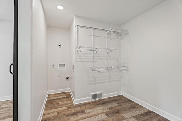 laundry room with visible vents, hookup for an electric dryer, baseboards, and wood finished floors