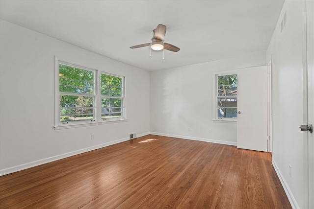 spare room featuring a wealth of natural light, visible vents, baseboards, and wood finished floors