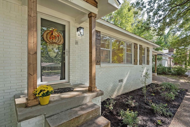 view of exterior entry featuring crawl space and brick siding