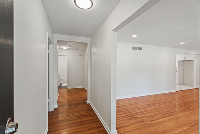 hall featuring baseboards, visible vents, attic access, recessed lighting, and light wood-type flooring